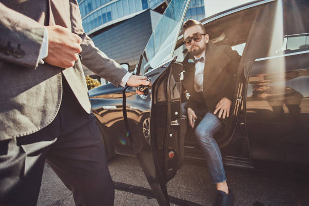 Chauffeur opening the door of a black executive Suburban for an arriving guest